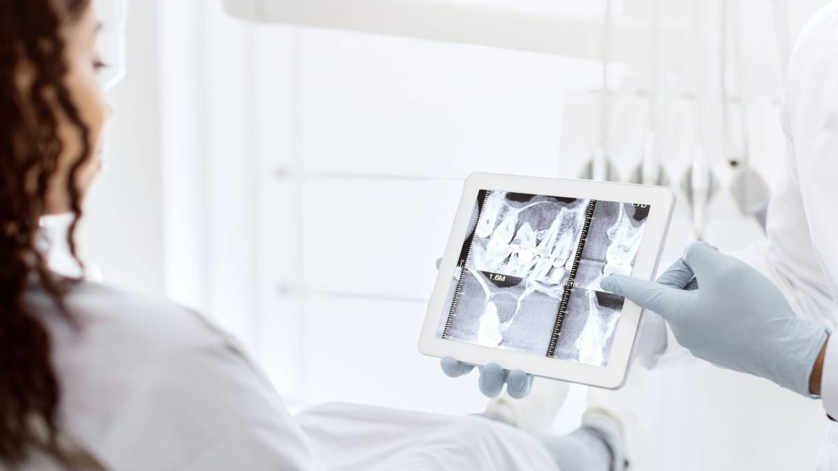A picture showing a dentist looking at a screen of x-rays
