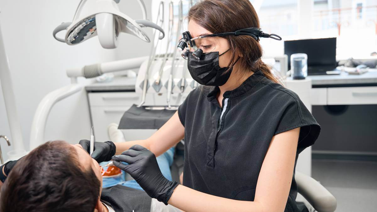 A picture of a dentist using dental equipment on patient