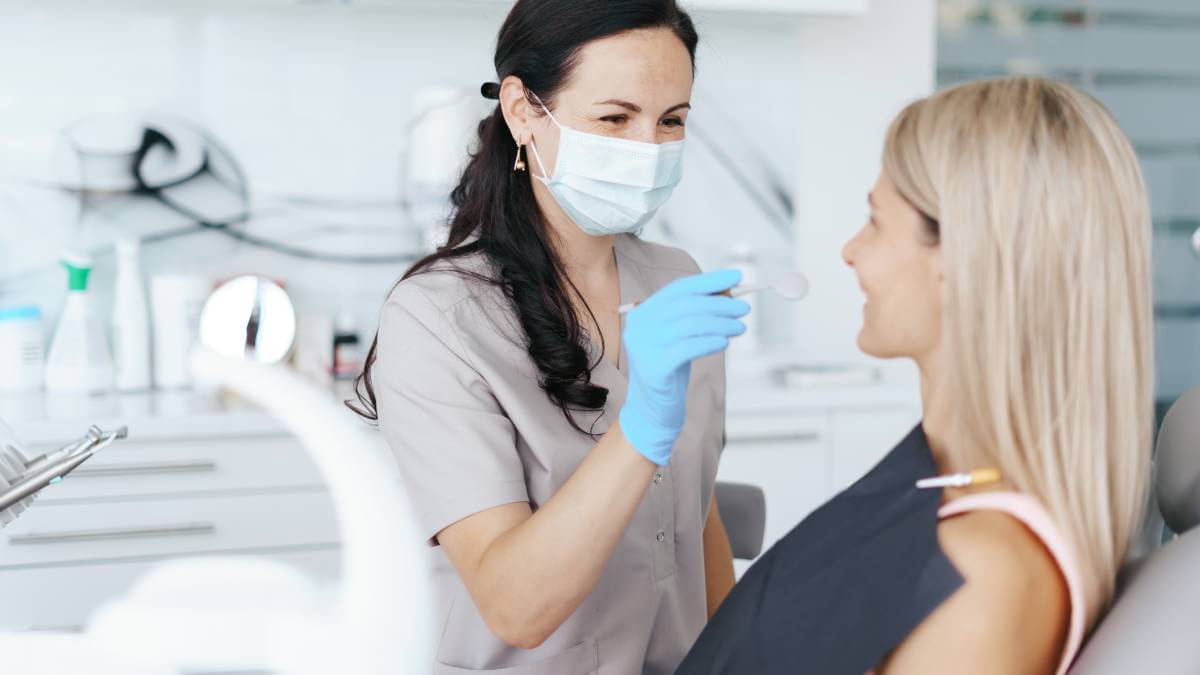 Dentist wearing a face cover and smiling at patient