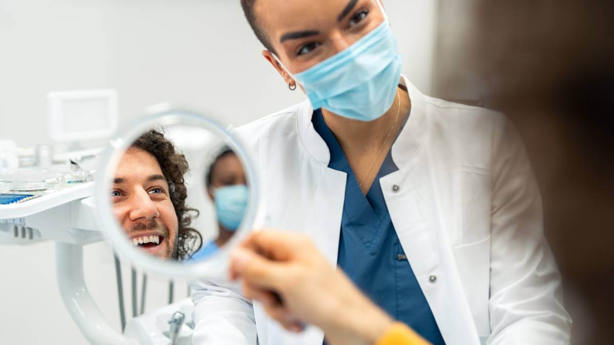 dentist smiling at patient looking in mirror